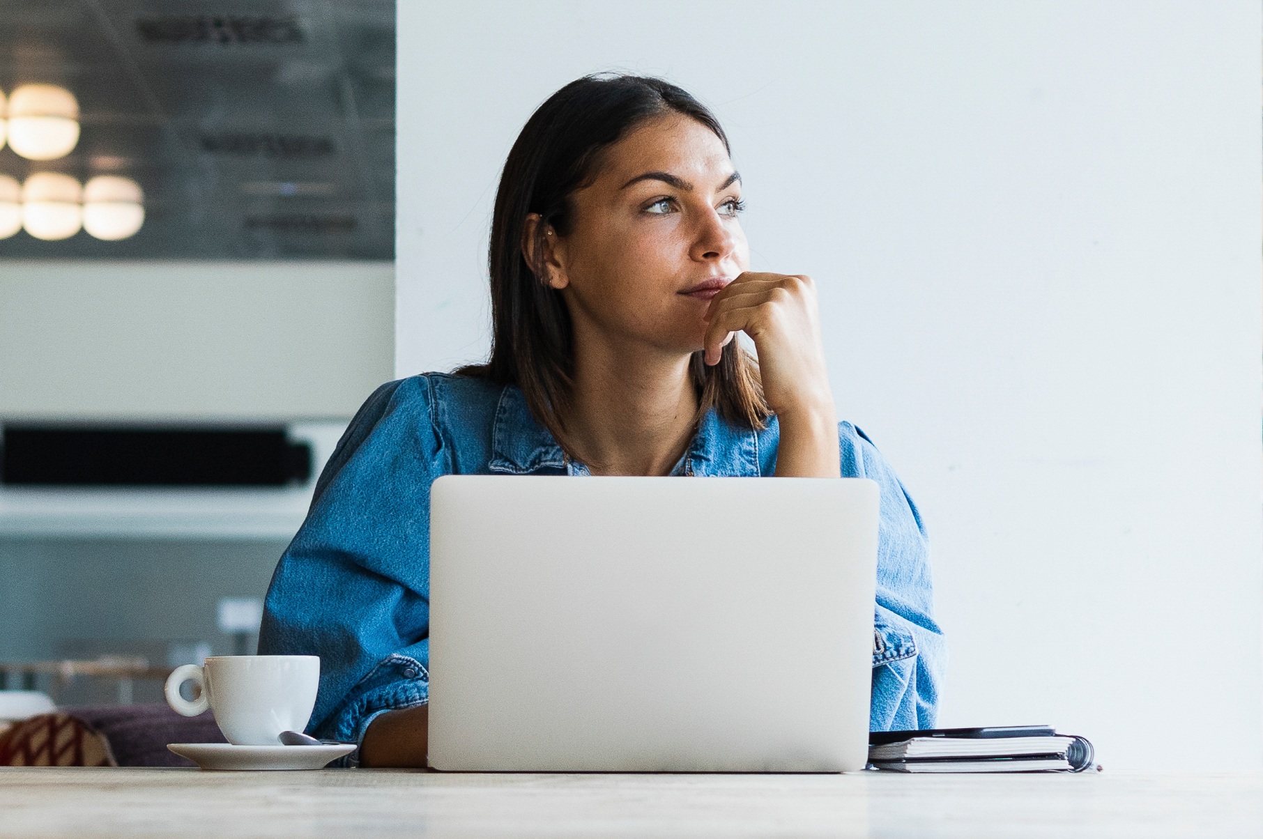 Woman sitting behind laptop and looking into the distance
