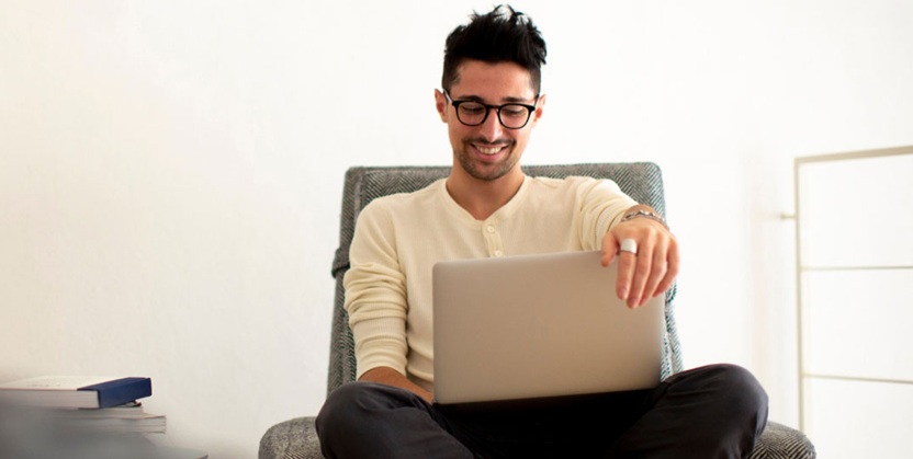 Person sitting comfortably in a chair working on a laptop at home.