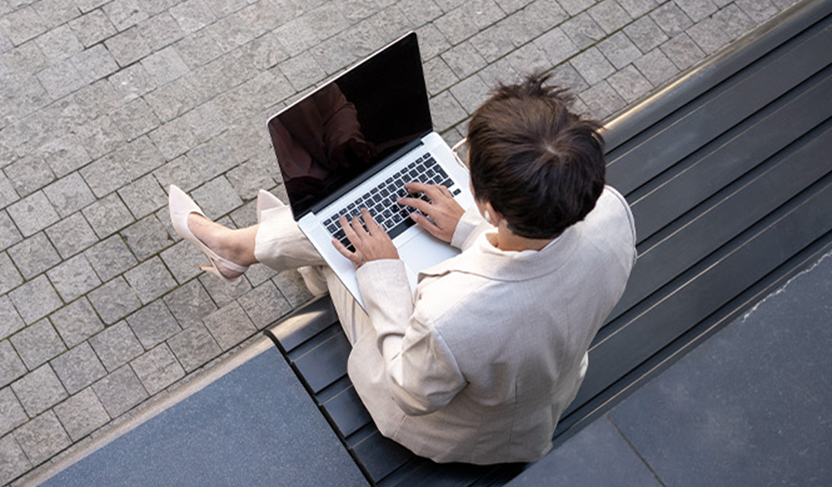 A lady in a professional attire sitting on a platform with a laptop on her lap