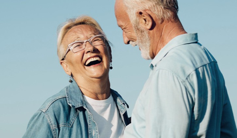 Older couple standing together outdoors, enjoying a calm moment under a clear blue sky.