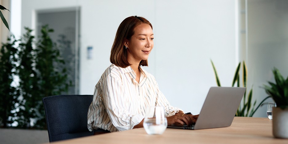 Person working on a laptop in a modern office setting.